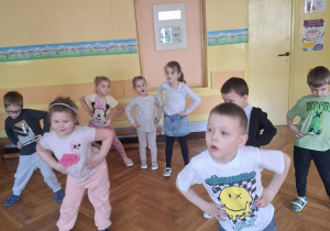 Grupa dzieci na sali gimnastycznej ćwiczy z p.prowadzącym