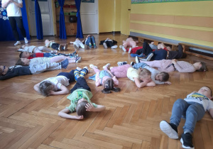 Grupa dzieci na sali gimnastycznej ćwiczy z p.prowadzącym
