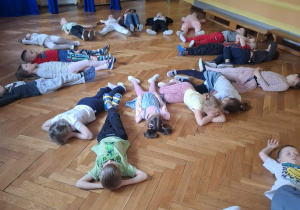 Grupa dzieci na sali gimnastycznej ćwiczy z p.prowadzącym