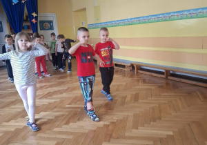 Grupa dzieci na sali gimnastycznej ćwiczy z p.prowadzącym