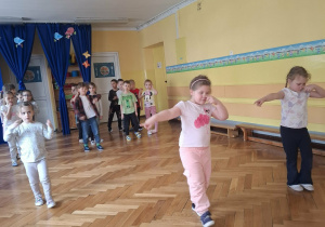 Grupa dzieci na sali gimnastycznej ćwiczy z p.prowadzącym