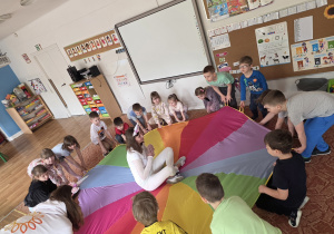 Dzieci biorą udział w zabawie z chustą animacyjną