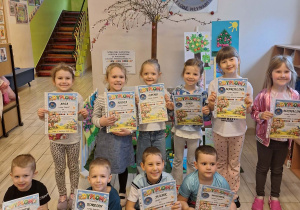 Dzieci pozują do zdjęcia pokazując swoje dyplomy za udział w konkursie