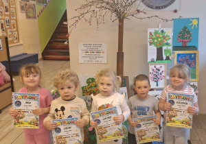 Dzieci pozują do zdjęcia pokazując swoje dyplomy za udział w konkursie