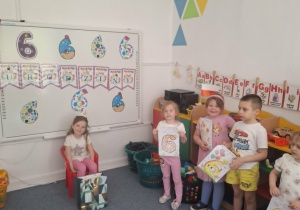 Dzieci stoją na dywanie i śpiewają Sarze sto lat