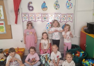 Sara siedzi na krześle i pozuje do zdjęcia z dziewczynkami