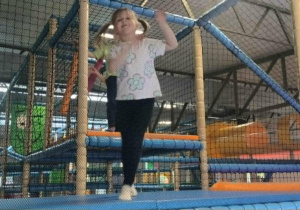 Dziewczynka bawi się na przyrządach na sali zabaw