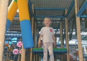 Dziewczynka bawi się na przyrządach na sali zabaw