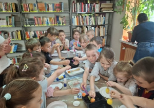 Grupa dzieci wykonuje przy stole pracę plastyczną