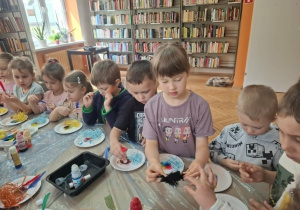 Grupa dzieci wykonuje przy stole pracę plastyczną