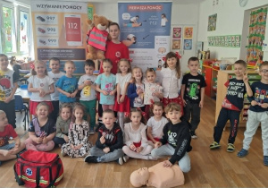 Dzieci stoją i pozują do zdjęcia z ratownikiem medycznym