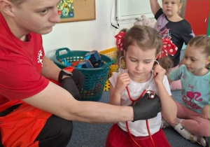 Dziewczynka trzyma na uszach stetoskop i słuch bicia swojego serca