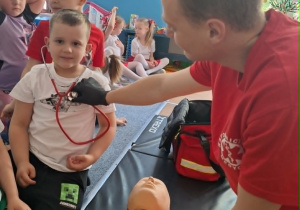 Chłopiec trzyma na uszach stetoskop i słuch bicia swojego serca