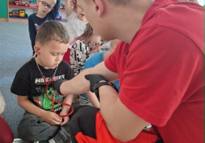 Chłopiec trzyma na uszach stetoskop i słuch bicia swojego serca