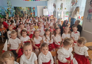 Dzieci siedzą na krzesłach i oglądają występy