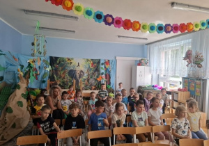 Dzieci siedzą na krzesłach i oglądają występy