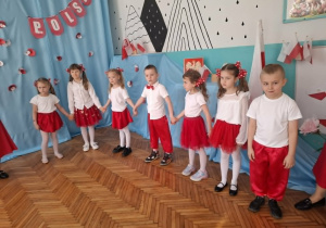 Dzieci stoją na środku sali i biorą udział w zabawie