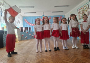Dzieci stoją na środku sali i śpiewają piosenkę