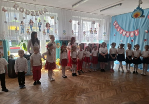Dzieci stoją na środku sali i biorą udział w zabawie