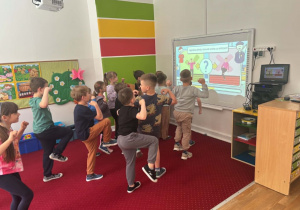 Dzieci ćwiczą wg wskazuwek pokazanych na tablicy multimedialnej