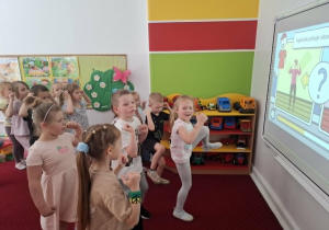 Dzieci ćwiczą wg wskazuwek pokazanych na tablicy multimedialnej
