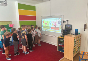 Dzieci ćwiczą wg wskazuwek pokazanych na tablicy multimedialnej