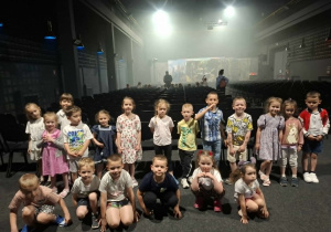 Dzieci pozują do zdjęcia w teatrze na tle dekoracji