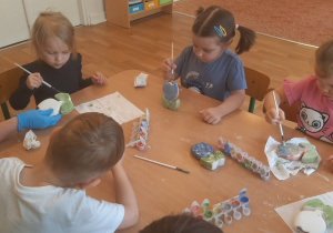 Dzieci pokrywają gliniany kwiatek specjalnymi farbami do ceramiki