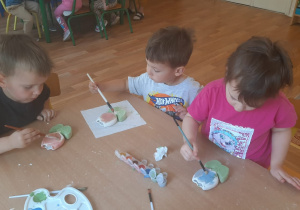 Dzieci pokrywają gliniany kwiatek specjalnymi farbami do ceramiki