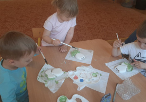 Dzieci pokrywają gliniany kwiatek specjalnymi farbami do ceramiki