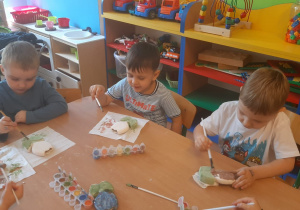 Dzieci pokrywają gliniany kwiatek specjalnymi farbami do ceramiki