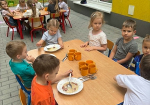 Dzieci jedzą obiad na tarasie przedszkolnyn