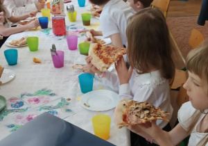 Dzieci spożywają pizzę