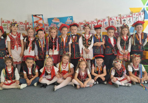 Cała grupa dzieci stoi i pozuje do zdjęcia w strojach krakowskich