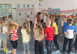 Dzieci stoją na dywanie i śpiewają Damianowi