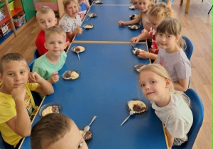 Dzieci siedzą przy stole i spożywają lody