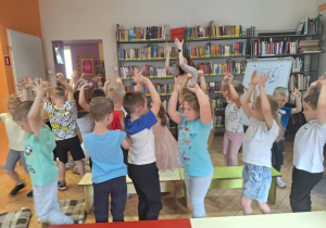 Dzieci stoją i bawią się z p.bibliotekarką