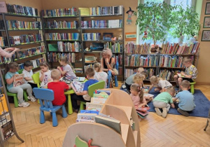 Grupa dzieci ogląda książki w kąciku czytelniczym