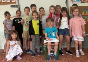 Chłopiec w czapeczce urodzinowej na głowie z grupą kolegów