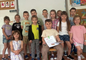 Chłopiec z czapeczką urodzinową na głowie z grupą kolegów