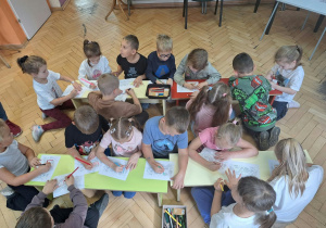 Dzieci kolorują kredkami obrazki