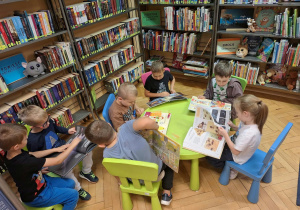 Grupa dzieci ogląda książki w kąciku czytelniczym