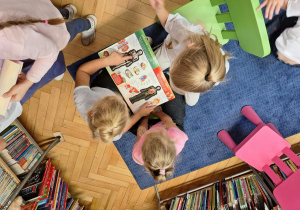 Grupa dzieci ogląda książki w kąciku czytelniczym