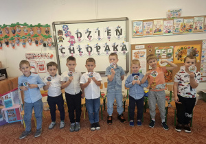 Chłopcy stoją na dywanie i pozują do zdjęcia, trzymając w ręku medal wspaniałego chłopca