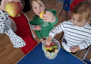 Trzy dziewczynki oglądają różne gatunki jabłek