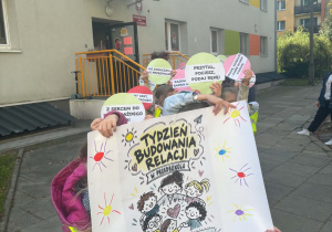 Dzieci idą na spacer z pozytywnymi hasłami na kartonikach