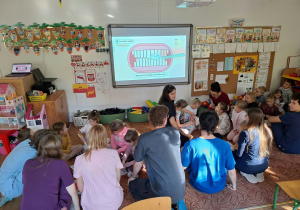Dzieci siedzą na dywanie ze studentami i rozmawiają na temat higieny jamy ustnej jamy