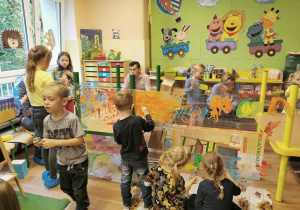Grupa dzieci maluje farbami na folii