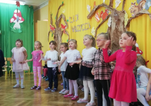 Dzieci stoją w rzędzie i śpiewają piosenkę