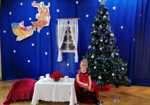 Dziewczynka pozuje do zdjęcia na tle bożonarodzeniowej dekoracji
